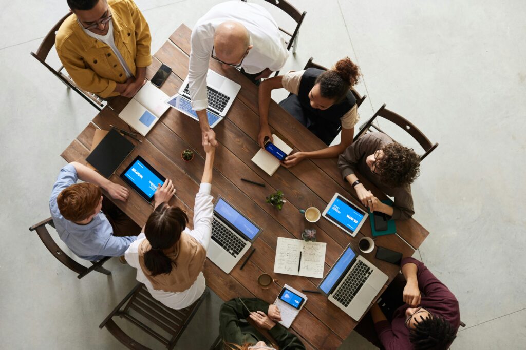 pexels photo 3183197 3183197 Top view of a diverse team collaborating in an office setting with laptops and tablets, promoting cooperation.